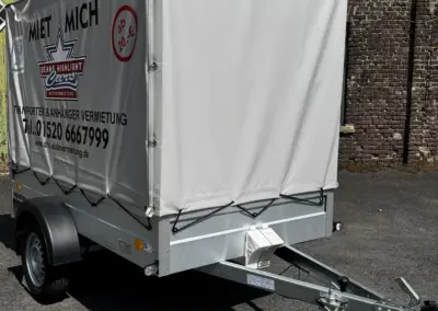 Ein Anhänger mit einer grauen Plane, der zur Vermietung angeboten wird.