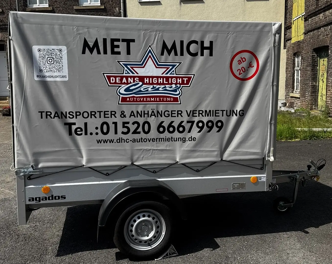 Grauer Anhänger von Agados mit Mietinformationen und Kontaktdaten für die Vermietung.