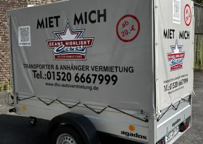 Grauer Anhänger mit Werbung für Mietdienstleistungen von Deans Highlight Cars.