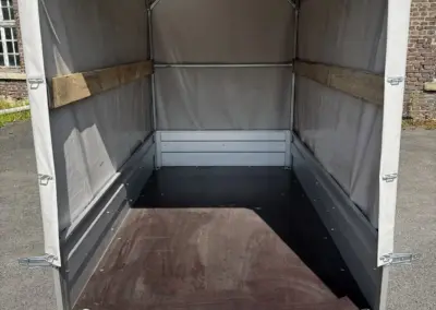 Leerer Anhänger mit einer Planenabdeckung und Holzlatten im Innenraum.