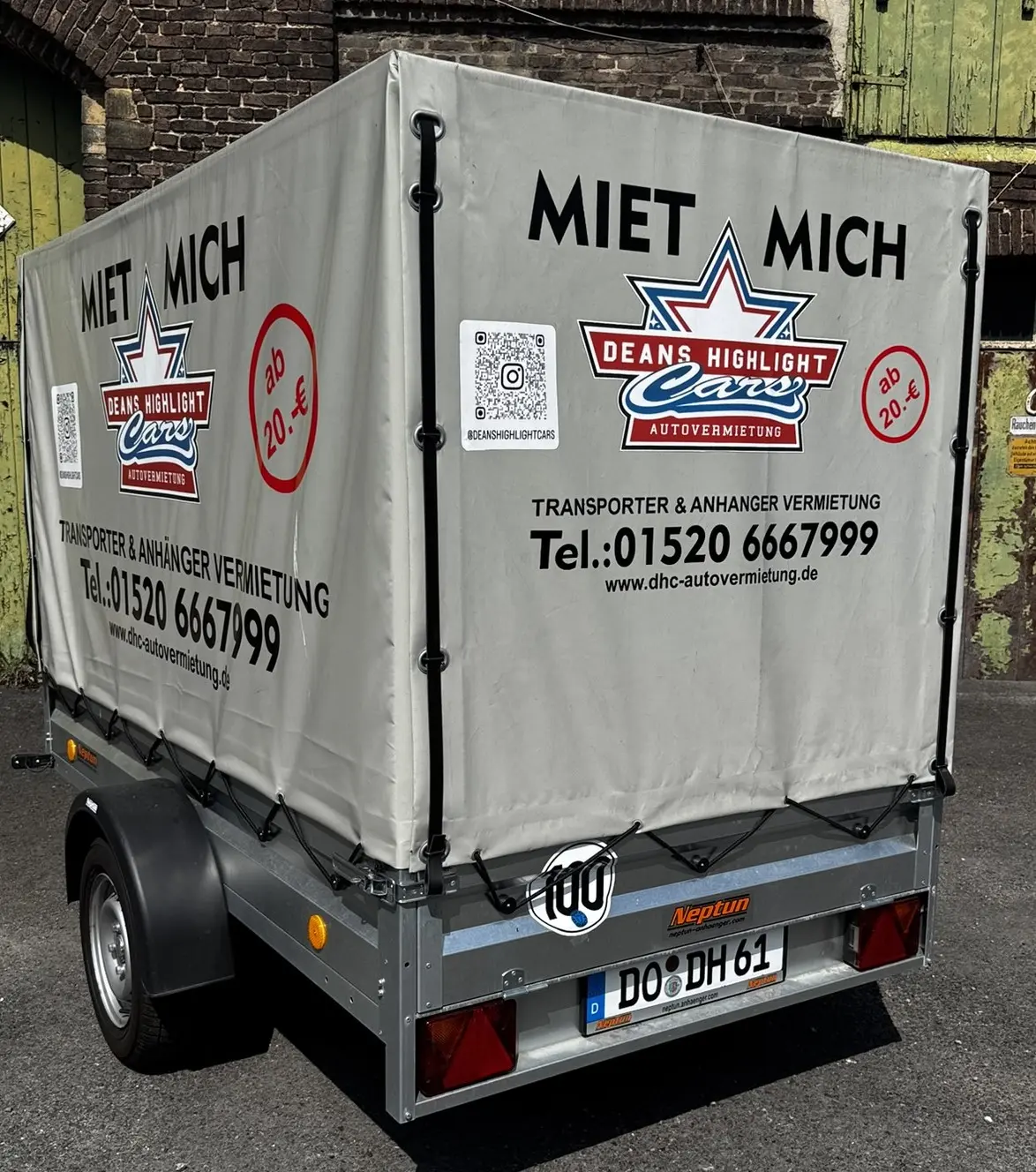 Ein Mietanhänger mit grauer Planenabdeckung und Werbung für Deans Highlight Cars.