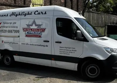 Weißer Transporter mit dem Logo von Deans Highlight Cars und Kontaktdaten auf der Seite.