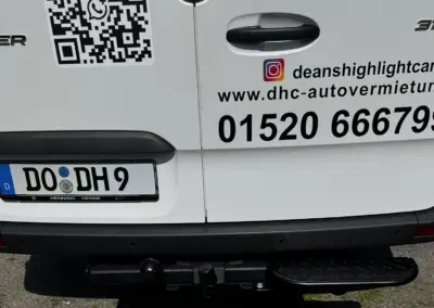 Rückansicht eines weißen Mercedes Sprinter mit QR-Code und Kontaktdaten auf dem Heck.