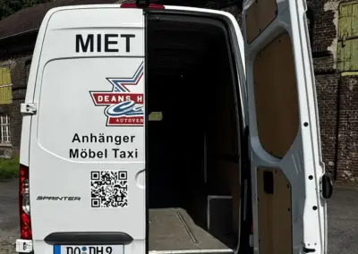 Weißer Mercedes-Benz Sprinter mit offener Heckklappe und Werbung auf der Rückseite.