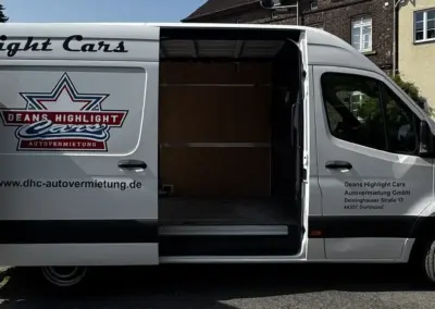 Weißer Sprinter Transporter mit geöffneten Türen und Firmenlogo von Deans Highlight Cars.