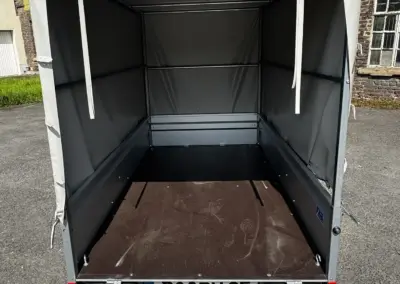 Offener Anhänger mit einer grauen Plane, die den Innenraum zeigt.