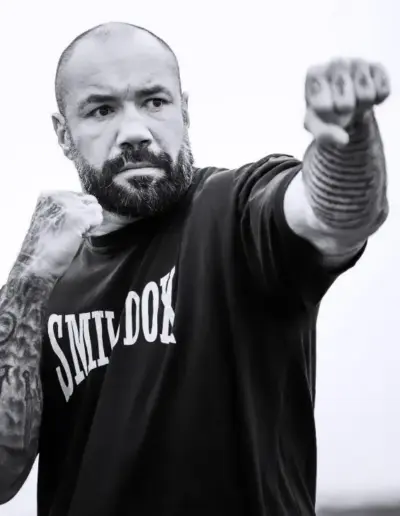 Mann mit Bart und Tattoos, der einen Schlag in einer Trainingspose ausführt.